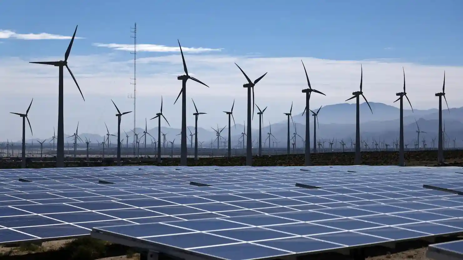 Wind turbines and solar panels representing renewable energy projects affected by federal permitting dispute