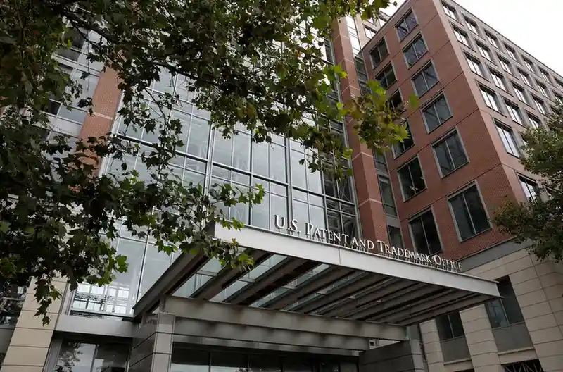 Federal Circuit courthouse with USPTO seal, patent files and logos of Apple, Google, Intel in foreground